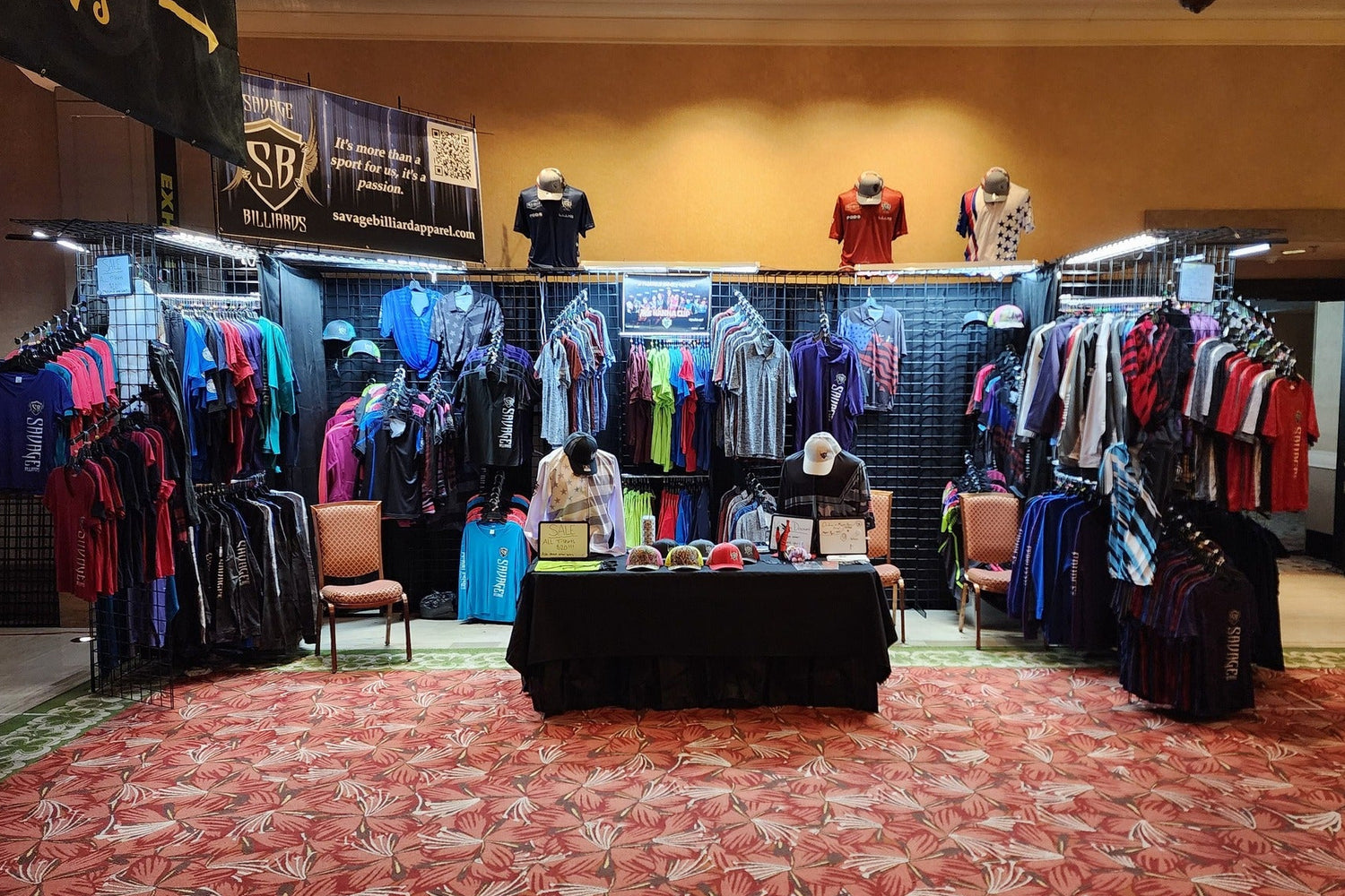 Clothing display setup in a large indoor space with chairs and tables.